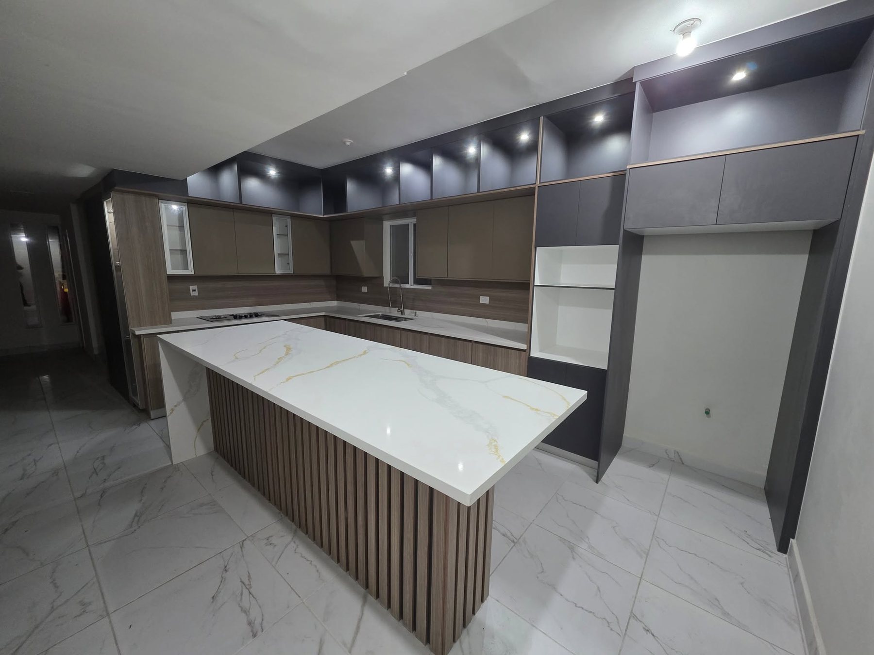 Cocina integral con isla de mármol y alacena iluminada, fabricada por HV Carpintería